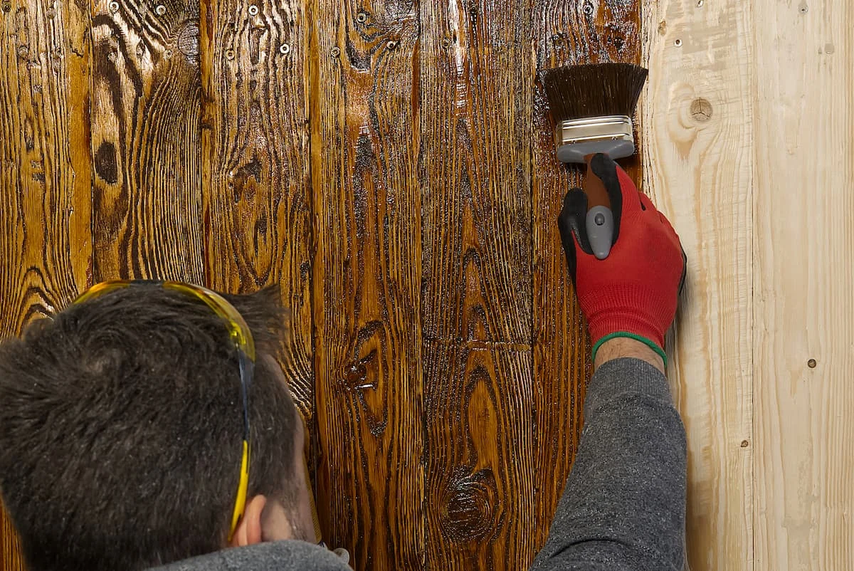 Tischler streicht Holz mit Wasserfarbe. Holzstruktur mit natürlichem Öl imprägniert.